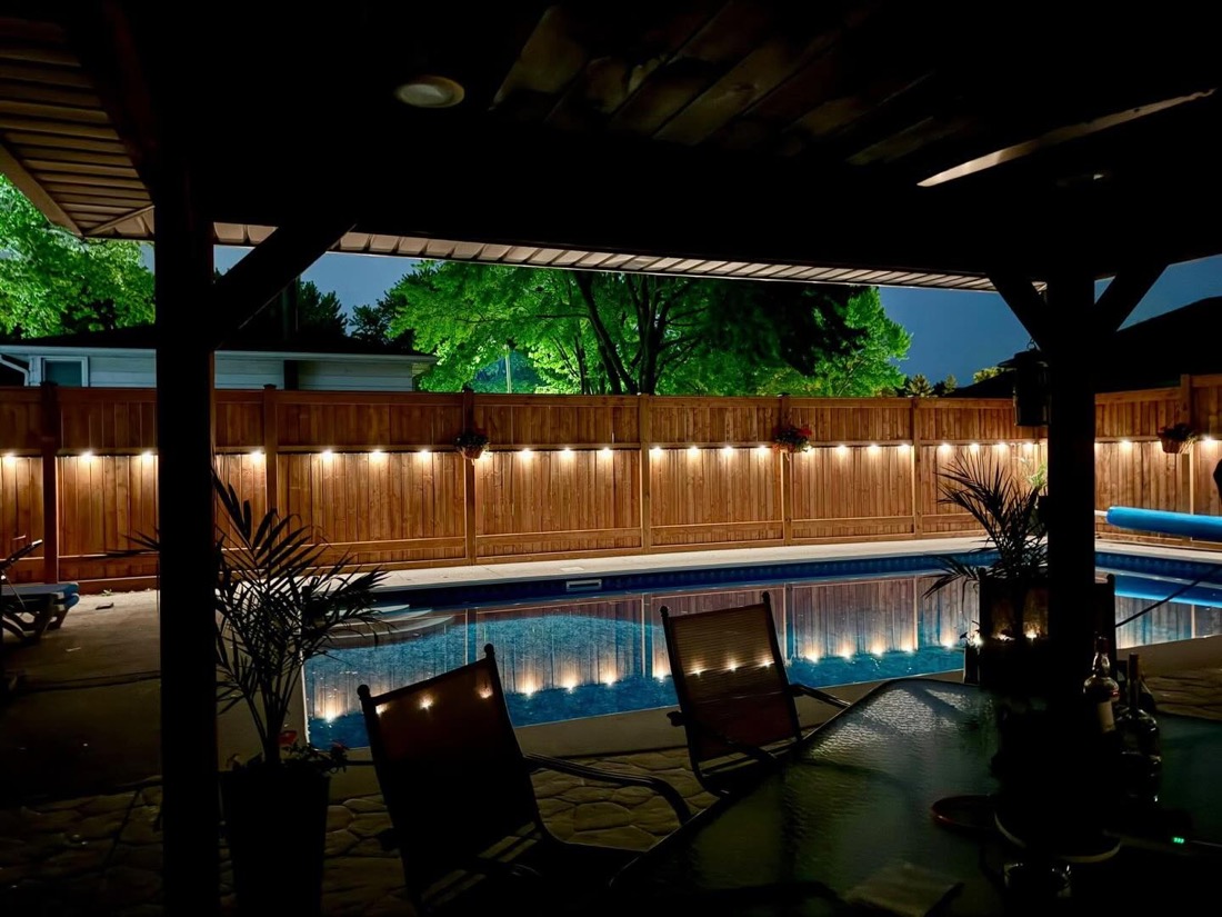 Backyard deck and pergola over a pool with permanent accent lighting